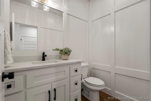 bathroom with wood finished floors, vanity, and toilet
