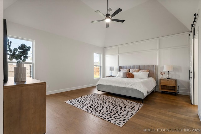 bedroom featuring multiple windows, high vaulted ceiling, dark wood finished floors, and a barn door