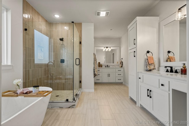 full bath with a freestanding bath, visible vents, a sink, two vanities, and a stall shower
