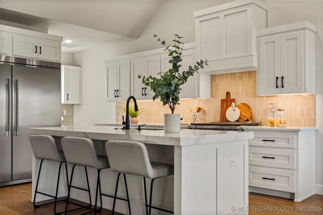 13676 S 23rd St, Bixby, OK 74008 - kitchen with stainless steel built in refrigerator, a kitchen island with sink, backsplash, white cabinetry, and a kitchen bar