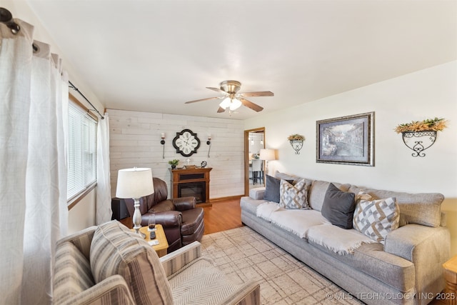 904 N Morningside Dr, Vinita, OK 74301 - living area featuring wood walls, a ceiling fan, a glass covered fireplace, and light wood-style flooring