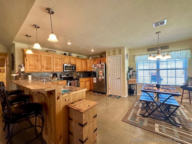 kitchen with stainless steel appliances, backsplash, visible vents, light tile patterned floors, and a peninsula