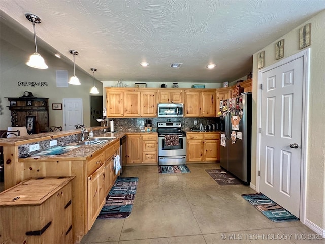 kitchen featuring hanging light fixtures, a sink, decorative backsplash, stainless steel appliances, and a peninsula