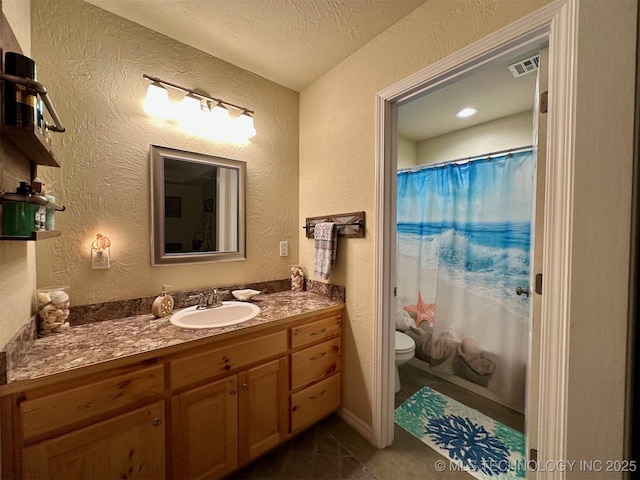 bathroom with toilet, a textured wall, and vanity