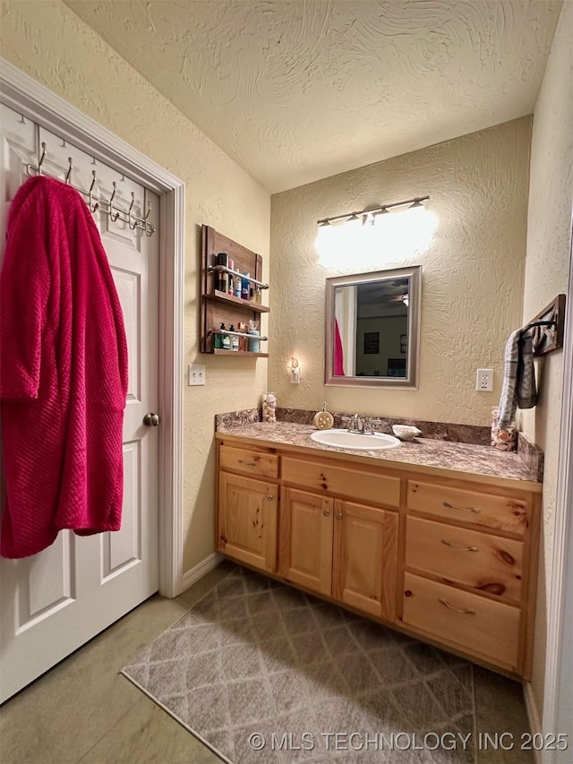 bathroom featuring a textured wall, vanity, and a textured ceiling