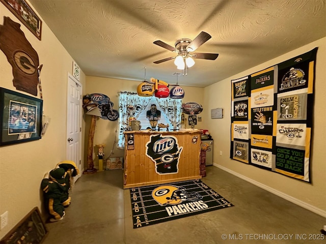 interior space with ceiling fan, concrete floors, a textured ceiling, and baseboards