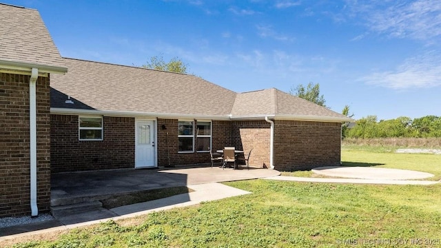 35041 Cohea Ln, Ketchum, OK 74331 - rear view of house featuring a yard, roof with shingles, brick siding, and a patio area