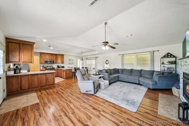 35041 Cohea Ln, Ketchum, OK 74331 - living room with vaulted ceiling, a ceiling fan, light wood-style floors, a fireplace, and visible vents