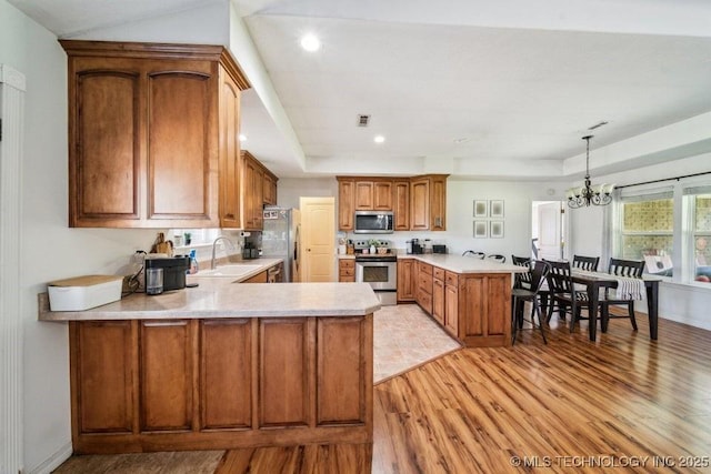 35041 Cohea Ln, Ketchum, OK 74331 - kitchen featuring a peninsula, light wood-style floors, stainless steel appliances, and a tray ceiling