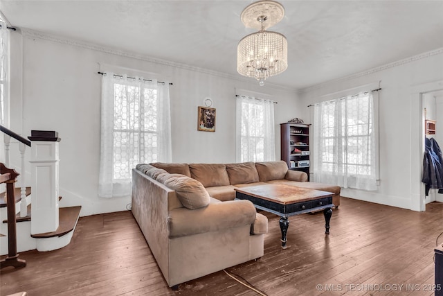 living area featuring hardwood / wood-style flooring, crown molding, a notable chandelier, and stairs
