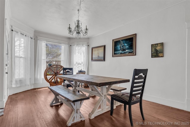 dining space with hardwood / wood-style floors, baseboards, a notable chandelier, and crown molding