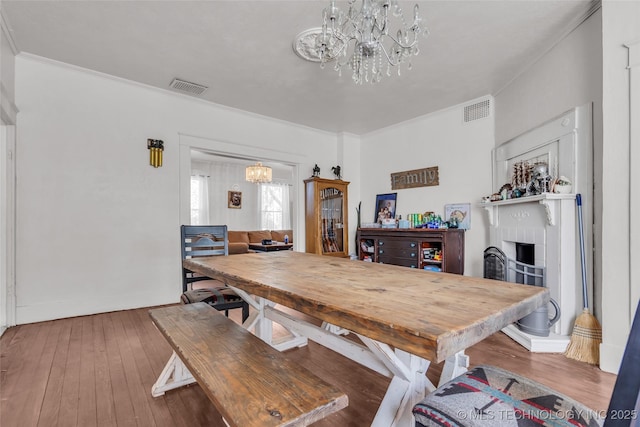 dining area with hardwood / wood-style floors, visible vents, and a notable chandelier