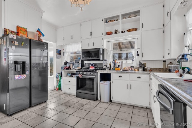 kitchen with a sink, light tile patterned floors, white cabinetry, light countertops, and appliances with stainless steel finishes