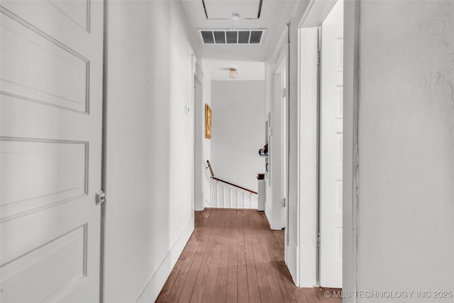 corridor with an upstairs landing, attic access, hardwood / wood-style flooring, baseboards, and visible vents