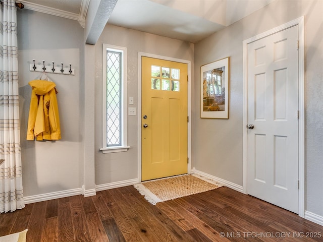 foyer with crown molding, baseboards, and dark wood finished floors