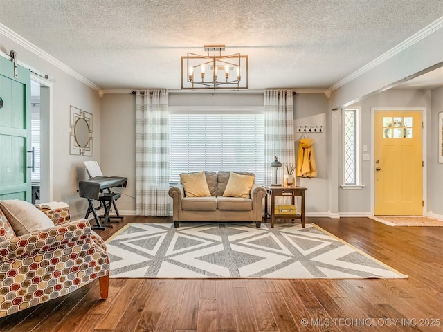 living area with an inviting chandelier, a textured ceiling, wood finished floors, and ornamental molding