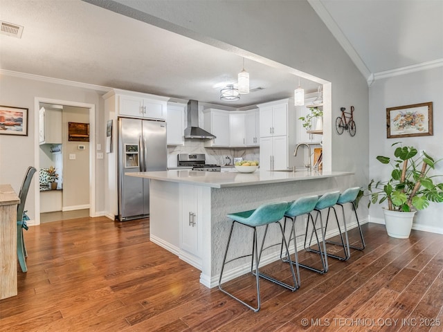 kitchen featuring dark wood-style floors, wall chimney exhaust hood, visible vents, ornamental molding, and appliances with stainless steel finishes