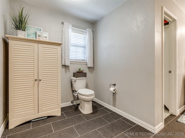 bathroom with baseboards, tile patterned floors, and toilet