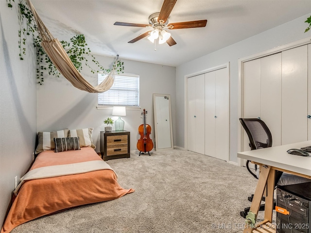 carpeted bedroom featuring a ceiling fan and two closets