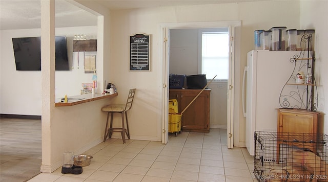 705 S Garfield Ave, Wagoner, OK 74467 - kitchen featuring baseboards, light tile patterned flooring, and freestanding refrigerator
