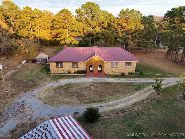 view of front of property featuring a front lawn, driveway, and metal roof