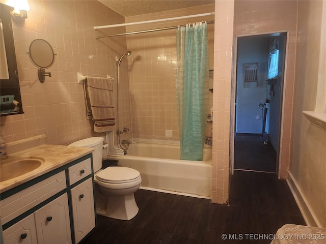 bathroom featuring wood finished floors, vanity, shower / tub combo with curtain, tile walls, and toilet