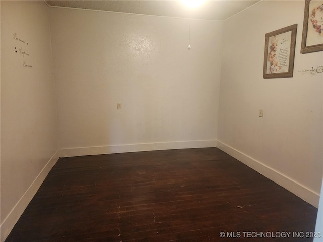 unfurnished room featuring baseboards and dark wood-style floors