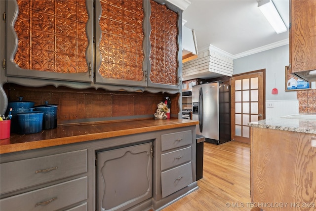 kitchen featuring light wood finished floors, a wainscoted wall, gray cabinets, ornamental molding, and stainless steel refrigerator with ice dispenser