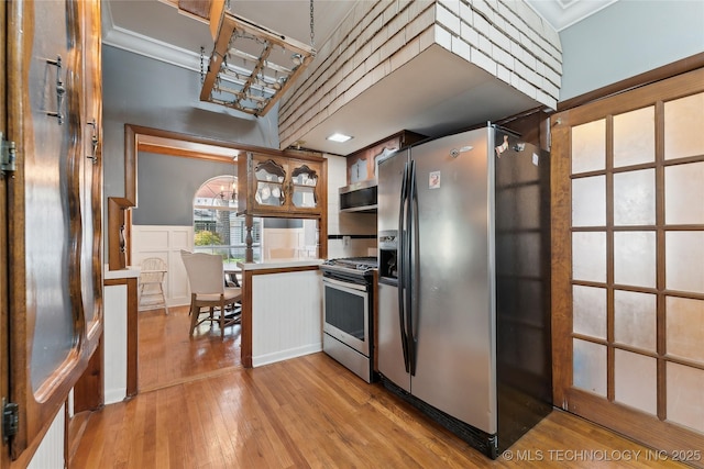 kitchen featuring a peninsula, light wood-style flooring, light countertops, and appliances with stainless steel finishes