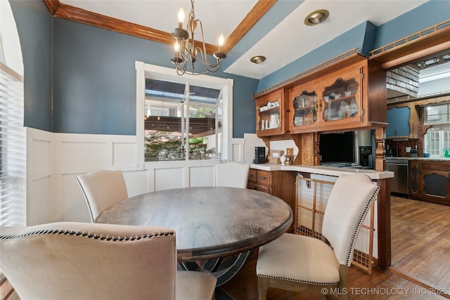 dining room featuring wood finished floors, a decorative wall, wainscoting, and an inviting chandelier