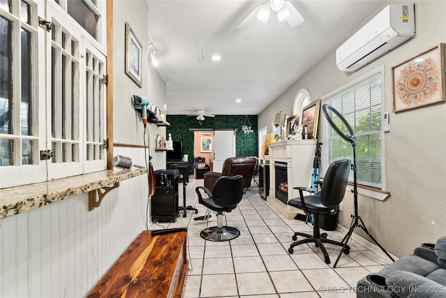 office area with a wall mounted air conditioner, a ceiling fan, a lit fireplace, and light tile patterned flooring