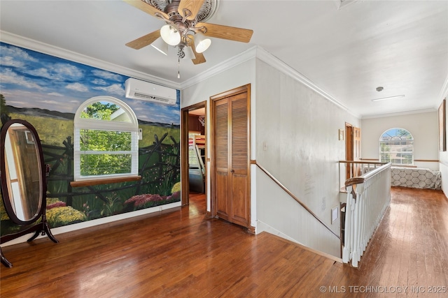 interior space with a wall mounted air conditioner, ornamental molding, ceiling fan, and wood finished floors