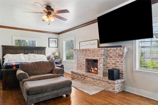 bedroom featuring wood finished floors, baseboards, ornamental molding, and a brick fireplace