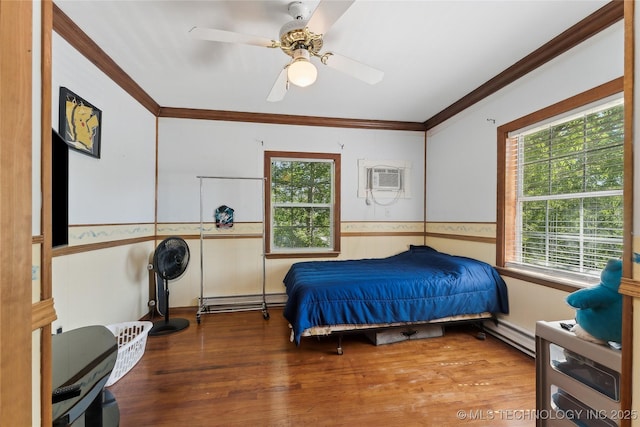 bedroom featuring a baseboard heating unit, wood finished floors, a wall unit AC, and ornamental molding