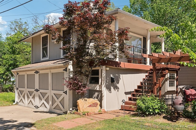 rear view of property featuring a garage and stairway