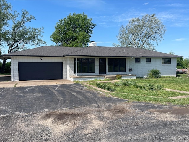 ranch-style home with brick siding, driveway, a chimney, and a garage