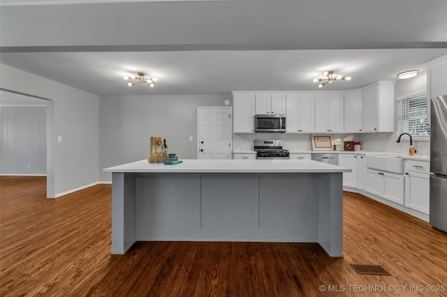 507 W Quincy St, Broken Arrow, OK 74012 - kitchen with appliances with stainless steel finishes, a sink, dark wood-style floors, a center island, and light countertops