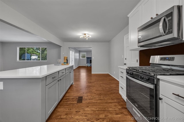 507 W Quincy St, Broken Arrow, OK 74012 - kitchen featuring appliances with stainless steel finishes, light countertops, dark wood finished floors, a kitchen island, and white cabinetry