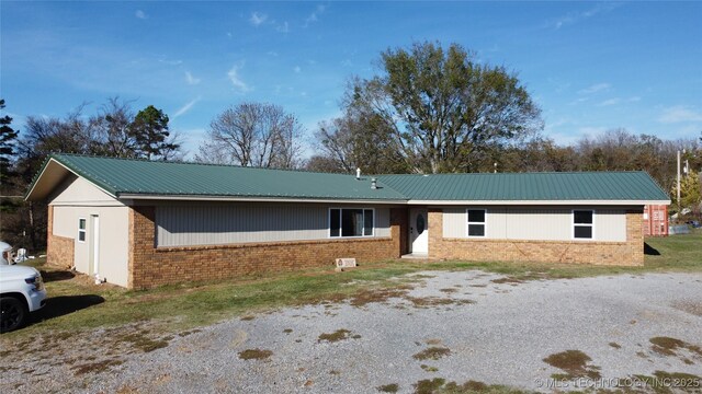 ranch-style home featuring brick siding and metal roof