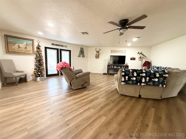living area with a ceiling fan, wood finished floors, a textured ceiling, baseboards, and recessed lighting