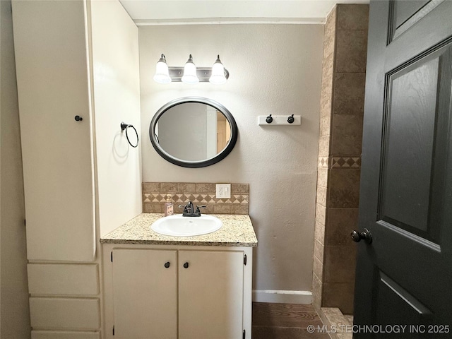 bathroom with baseboards, vanity, and backsplash