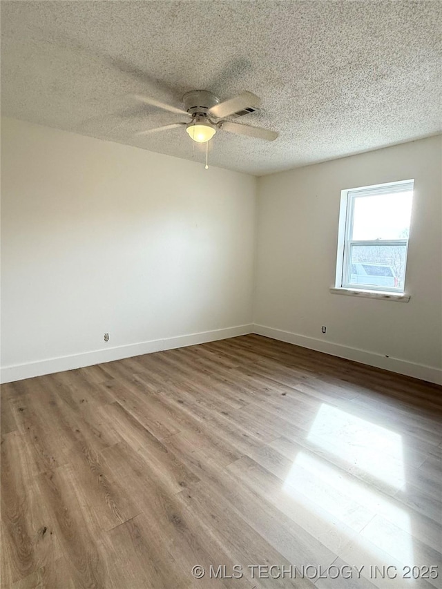 unfurnished room featuring wood finished floors, a textured ceiling, a ceiling fan, and baseboards