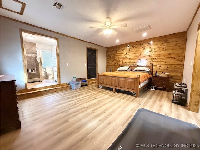 bedroom with wooden walls, wood finished floors, visible vents, a ceiling fan, and crown molding