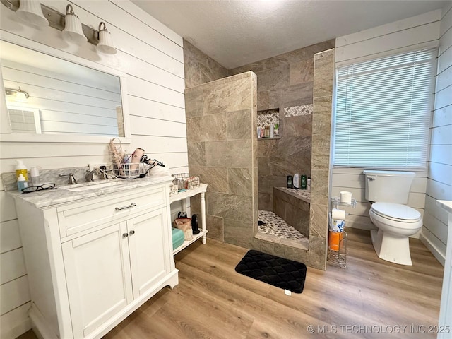 bathroom with wood finished floors, a textured ceiling, vanity, walk in shower, and toilet