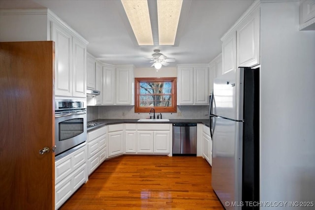 509 NE 10th St, Wagoner, OK 74467 - kitchen featuring dark countertops, a sink, decorative backsplash, stainless steel appliances, and white cabinetry