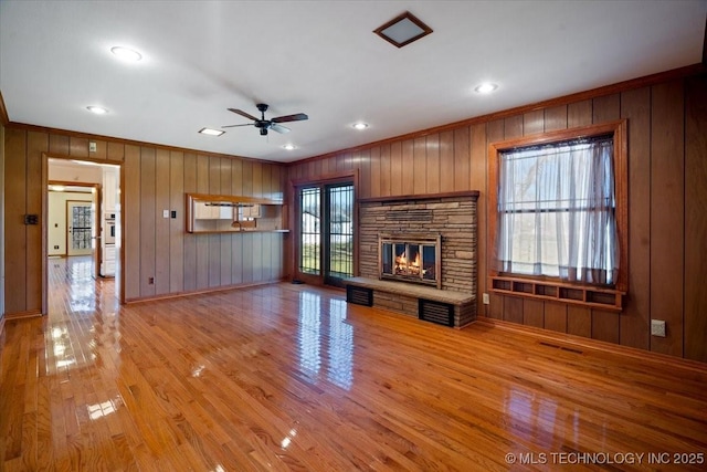 509 NE 10th St, Wagoner, OK 74467 - unfurnished living room with wood walls, crown molding, a stone fireplace, and light wood-style flooring