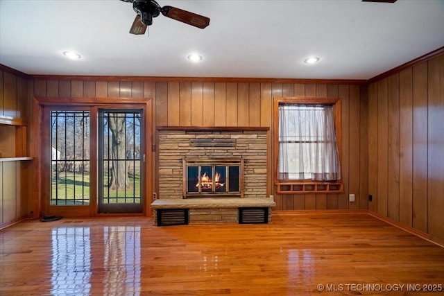 509 NE 10th St, Wagoner, OK 74467 - unfurnished living room featuring a ceiling fan, wood finished floors, a stone fireplace, and a healthy amount of sunlight