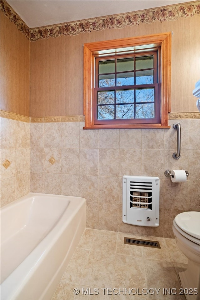509 NE 10th St, Wagoner, OK 74467 - full bathroom with a bath, a wainscoted wall, toilet, tile walls, and heating unit