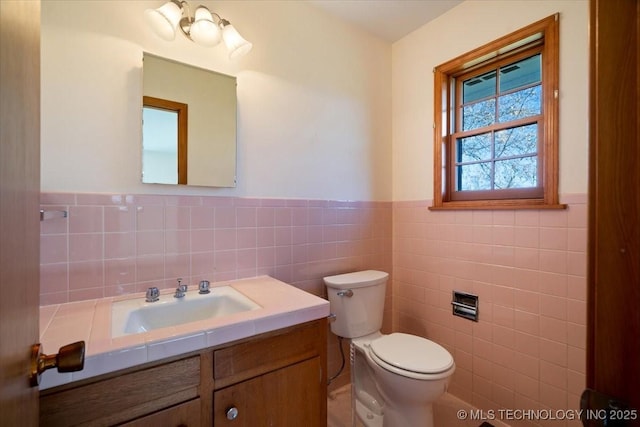 509 NE 10th St, Wagoner, OK 74467 - bathroom featuring tile walls, wainscoting, vanity, and toilet
