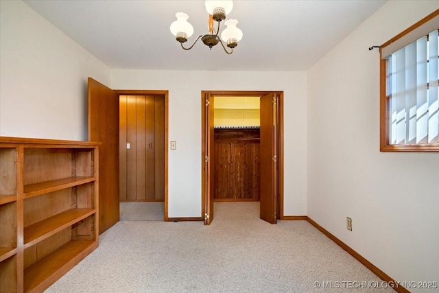 509 NE 10th St, Wagoner, OK 74467 - unfurnished bedroom featuring a walk in closet, carpet floors, a closet, baseboards, and a notable chandelier
